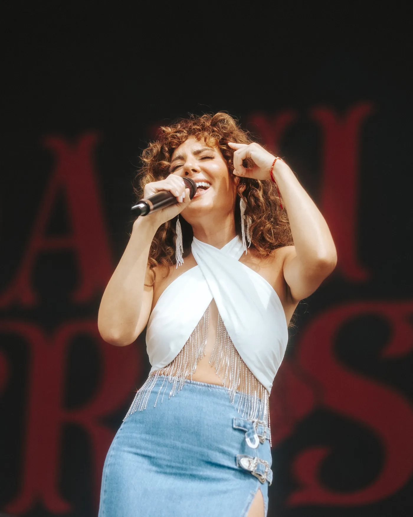 Dani Rose singing live on a festival stage, her name in red letters behind her
